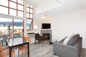 uma sala de estar com um sofá, uma mesa e uma lareira em Alpenglow Lodge Junior Penthouse by MVA em Whistler