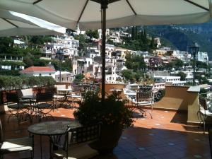 a patio with tables and chairs and an umbrella at Hotel Posa Posa in Positano