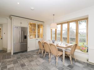 a kitchen with a table with chairs and a refrigerator at Wood Stanway House in Cheltenham
