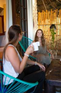 deux femmes assises dans un hamac avec une tasse de café dans l'établissement Sirenas Caribbean Rooms Holbox, à Holbox