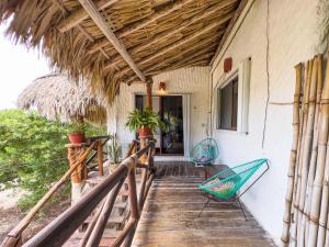a porch of a house with two chairs on it at Sirenas Caribbean Rooms Holbox in Holbox Island +87 photos