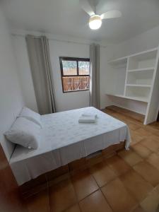 1 dormitorio con cama blanca y ventana en Casa com Jacuzzi aquecida praia do Lazaro, en Ubatuba
