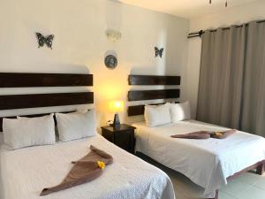 2 camas en una habitación con mariposas en la pared en Hotel La Casa del Capi en Holbox Island