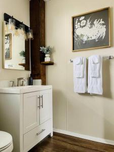 a bathroom with a sink and a toilet and towels at Abode à la Mode / Centrally Located 2BR/1BA Home in Evansville
