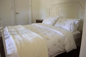 a white bed with a white comforter with birds on it at Bickley Valley Cottage in Bickley