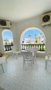 Zimmer mit 2 Fenstern, einem Tisch und Stühlen in der Unterkunft Bungalow S+1 au port de Kantaoui, Sousse. Avec balcon offrant une panorama envoûtant in Sousse