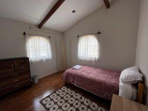 a bedroom with a bed and a dresser and two windows at Casa San Lorenzo in Huánuco