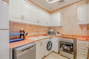 a kitchen with white cabinets and a sink and a dishwasher at Beautiful Al Marjan sea view Apartment in Ras al Khaimah