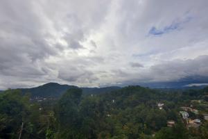 een uitzicht op een stad in de bergen onder een bewolkte hemel bij Gannoru Hatana Villa in Kandy
