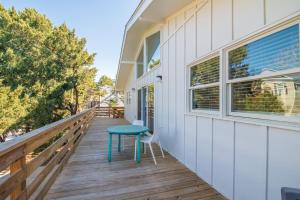 a wooden balcony with a blue table on the side of a house at Cozy Beach House Steps from the Shore: 4 Bedroom in Pawleys Island