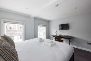 a white bedroom with a white bed and a desk at Hausd - Soho in London
