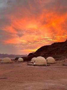 un gruppo di cupole nel deserto con un tramonto di Rum Mars camp a Wadi Rum