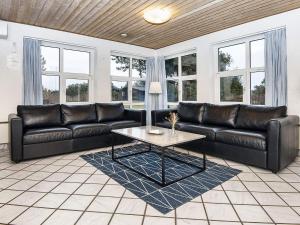 a living room with black leather couches and a coffee table at 12 person holiday home in Glesborg in Fjellerup