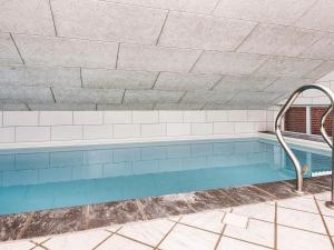 a swimming pool in a building with a blue at 12 person holiday home in Glesborg in Fjellerup