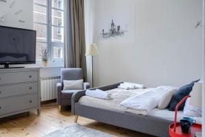 ein Schlafzimmer mit einem Bett, einem Stuhl und einem TV in der Unterkunft Corolla Apartments Nowy Świat 52 Stare Miasto in Warschau
