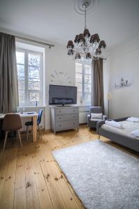 ein Wohnzimmer mit einem Bett, einem Tisch und einem TV in der Unterkunft Corolla Apartments Nowy Świat 52 Stare Miasto in Warschau