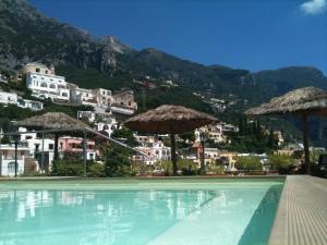 a swimming pool with umbrellas in front of a city at Hotel Posa Posa in Positano