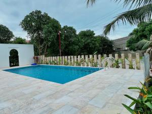 una piscina en un patio trasero con una valla de madera en Wanderlust Hotel en Mui Ne