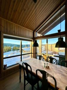 a large wooden table in a room with a large window at New cabin with jacuzzi, sauna and ski inout in Svingvoll