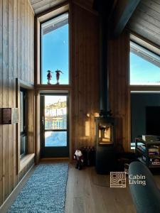 een woonkamer met 2 ramen en een open haard bij New cabin with jacuzzi, sauna and ski inout in Svingvoll