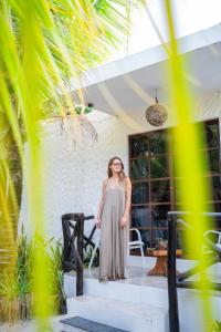 a woman standing on the stairs of a house at Sirenas Caribbean Rooms Holbox in Holbox Island