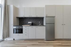 a kitchen with white cabinets and a stainless steel refrigerator at Coqueto Apartamento en Delicias in Madrid