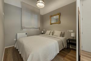 a bedroom with a white bed and a mirror at Coqueto Apartamento en Delicias in Madrid