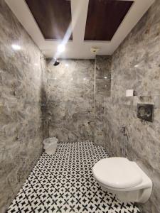 ein Bad mit einem WC und einem schwarz-weißen Fliesenboden in der Unterkunft PK Boutique Hotel in Noida