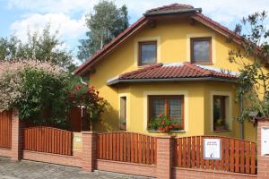 a yellow house with a wooden fence at Apartment BENCI in Jindrichuv Hradec