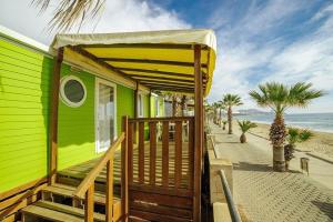 a green house on the beach with palm trees at Alannia Costa Dorada in Platja de l’Almadrava