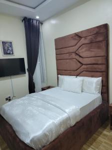Schlafzimmer mit einem großen Bett mit einem Kopfteil aus Holz in der Unterkunft Somek Homes2 in Lekki