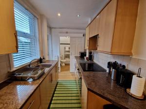 una cocina con armarios de madera y una alfombra verde en Cosy Luxury Home next to City Centre with Free Parking - Contractors & Relocators, en Coventry