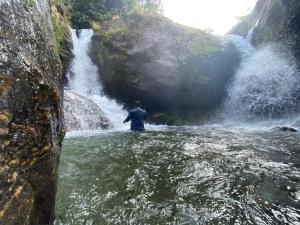a man standing in the water near a waterfall at Chumang River Nest in Thode