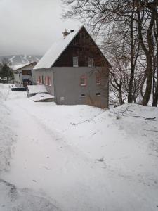 a barn covered in snow next to a snow covered road at Chata Na Rozcestí in Loučná pod Klínovcem