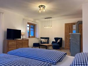 a bedroom with two beds and a tv and chairs at Ferienwohnungen LARA Wohnung 2 in Wallgau