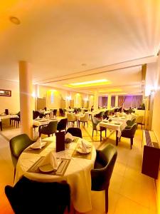 un restaurant avec des tables et des chaises blanches et un chercheur de table dans l'établissement Hotel Bab Mansour, à Meknès