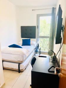 um quarto com uma cama, uma secretária e uma televisão em FIRA Gran Vía 2 - Private Rooms in a Shared Apartment - Habitaciones Privadas en Apartamento Compartido em L'Hospitalet de Llobregat