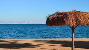 a straw umbrella on a beach near the water at Luxury Chalet in Mountain View 2 , El-Sokhna with Sea View , Pool View "Heated Pool" and Garden View Families Only in Ain Sokhna