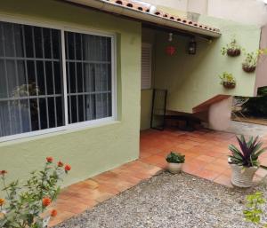 a green house with potted plants on a patio at Charmoso apto com clima de casa em Canasvieiras in Florianópolis