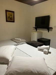 a room with two beds and a flat screen tv at Pousada House Sol & Praia in Torres