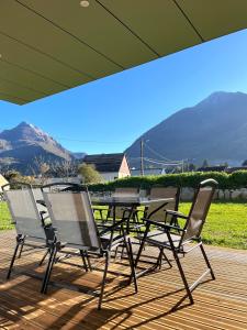 a table and chairs sitting on a deck with mountains in the background at Le Sailhet, maison de vacances in Pierrefitte-Nestalas