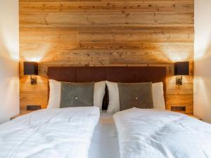 two beds in a bedroom with a wooden wall at Wagrainer TauernLodge 1 in Wagrain