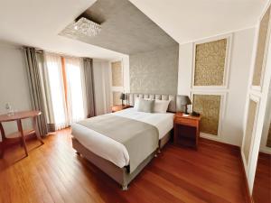Un dormitorio con una gran cama blanca y una mesa en Hotel Fundador, en Arequipa