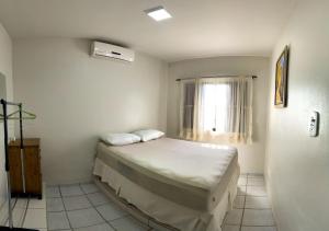 um pequeno quarto com uma cama e uma janela em Hospedagem Vó Lili Vô Ambrósio em Penha