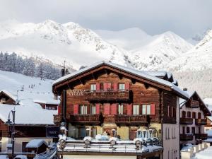 une maison en bois dans la neige avec des montagnes en arrière-plan dans l'établissement Camana Veglia, à Livigno