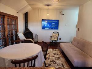 een woonkamer met een bank, een tafel en een tv bij Apartamento a 150m da Rua Coberta in Gramado