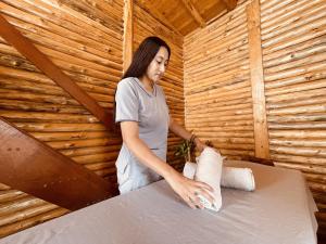 una mujer poniendo toallas en una cama en una sauna en Skyline Ecoliving Santa Elena, en Santa Elena
