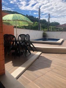 - une table et des chaises avec un parasol sur la terrasse dans l'établissement Casa temporada com Piscina, à Governador Celso Ramos