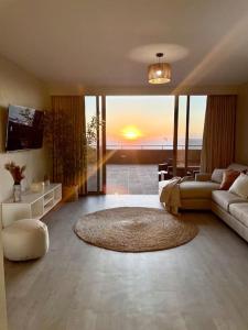 a living room with a couch and a living room with the sunset at Infinity Sunset Beachfront Apartment in Cape Town