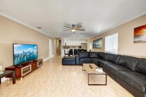 uma sala de estar com um sofá de couro preto e uma televisão de ecrã plano em Walk to Hollywood Beach Luxury 4BR Villa em Hollywood
